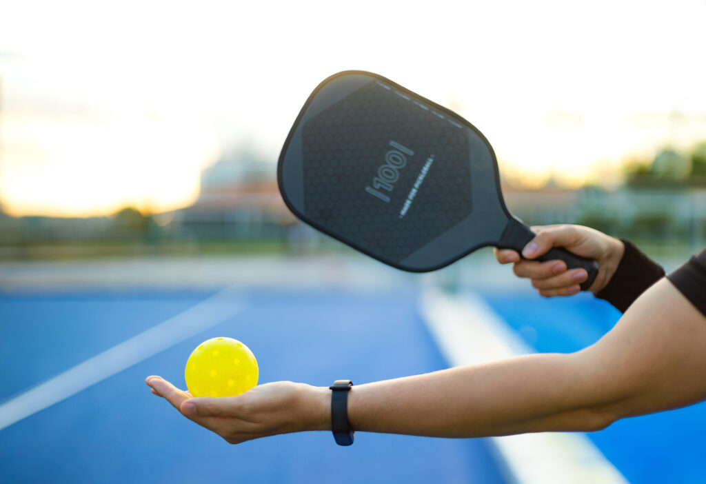Pickleball paddle with hand holding pickleball