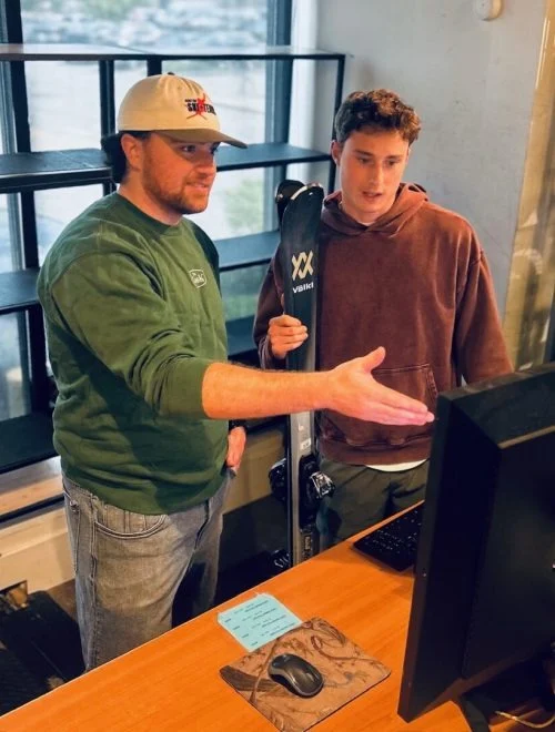 Boston Ski + Tennis employee helping customer with skis.